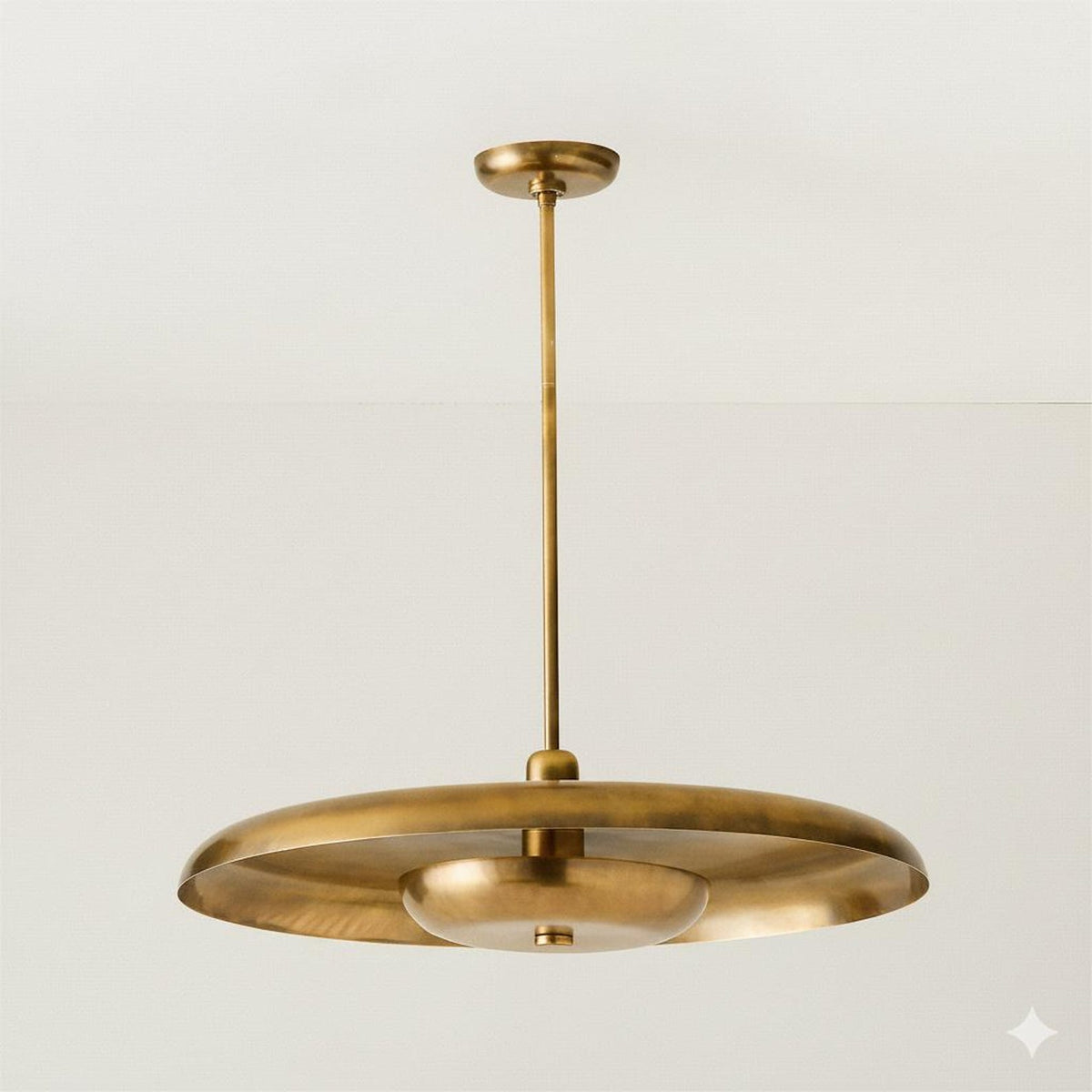 Brushed brass disc chandelier suspended from ceiling, showcasing sculpted form and soft uplighting.