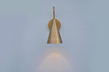 Front view of brass cone-shaped wall sconce casting warm downward light, crafted in brushed satin brass finish.