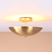 Elegant brushed brass bowl-shaped ceiling light emitting warm ambient glow from ceiling