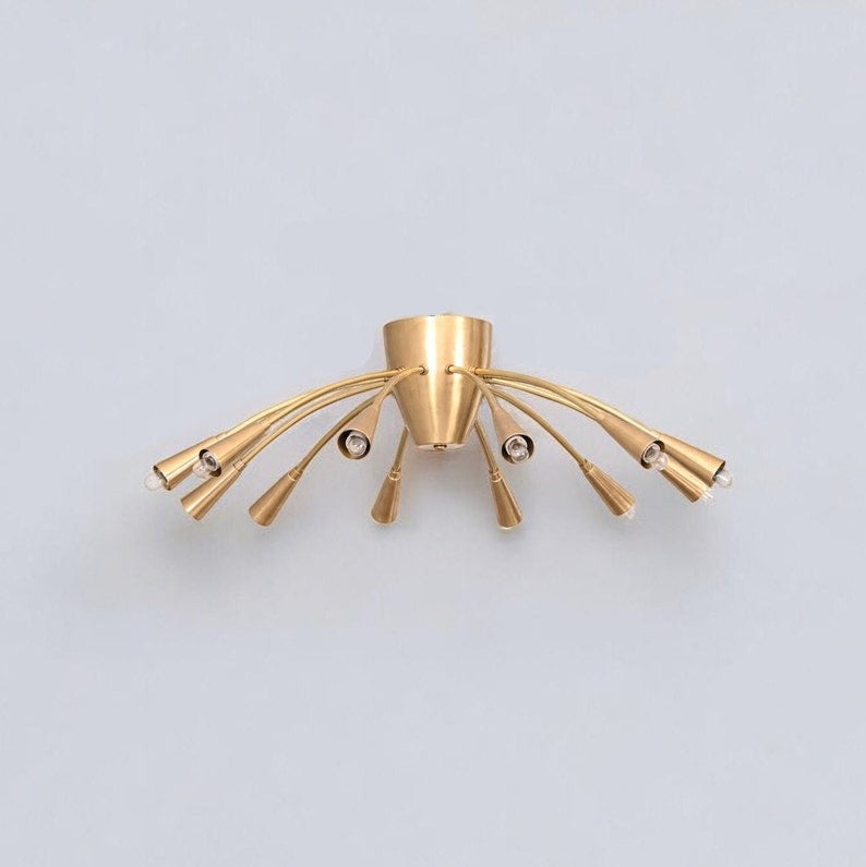 Angled view of the Cairo 12-light brass chandelier highlighting gracefully curved metal arms, tapered cone-shaped holders, and a compact central ceiling mount.