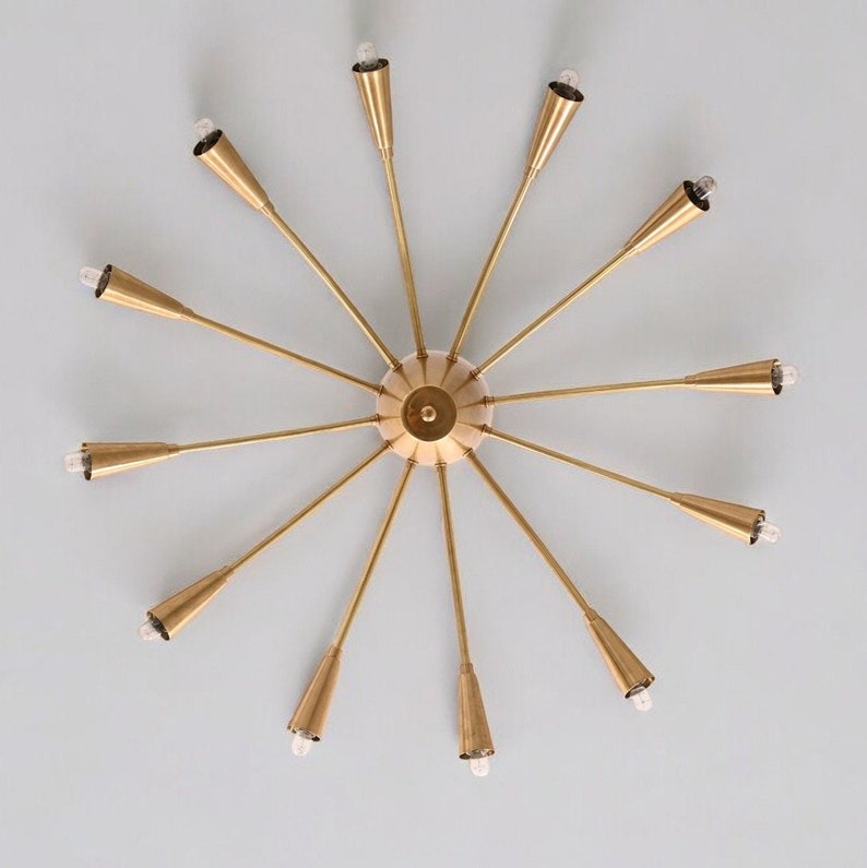 Bottom view of the Cairo 12-light Sputnik chandelier showcasing twelve radially arranged brass-tone arms, elongated cone bulb holders, and a symmetrical starburst-inspired structure.