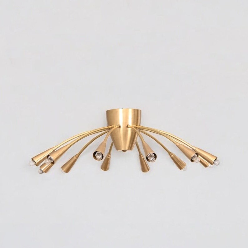 Front view of the Cairo 12-light Mid-Century Modern chandelier featuring curved brass-tone arms, tapered cone bulb holders, and a sculptural flush-mount ceiling design.