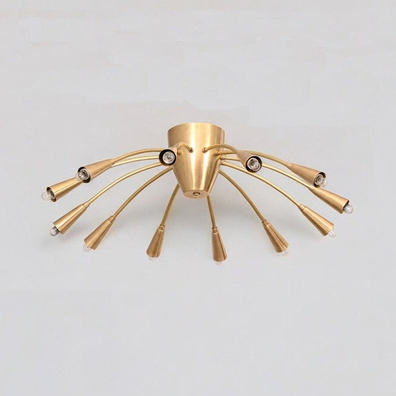 Full view of the Cairo 12-light flush-mount chandelier featuring a brushed brass-tone finish, twelve slender gooseneck arms, tapered metal holders, and a balanced radial design.