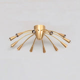 Full view of the Cairo 12-light flush-mount chandelier featuring a brushed brass-tone finish, twelve slender gooseneck arms, tapered metal holders, and a balanced radial design.