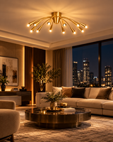 Cairo 12-light brass gooseneck chandelier illuminating a luxurious contemporary living room at night with a cream sectional sofa, black marble coffee table, warm ambient lighting, and city skyline views.