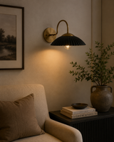 Cambria black fluted dome wall sconce with brass arm installed in a warm modern living room – Model 32785