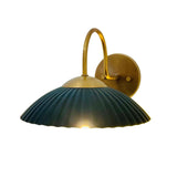 Cambria fluted dome wall sconce illuminated with warm light and brass curved arm – Model 32785