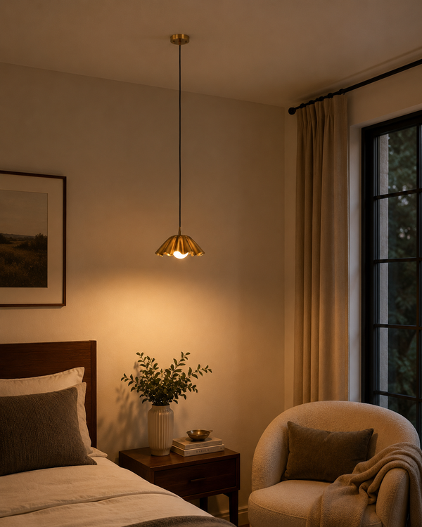 Cambria Fluted Petal Pendant Light installed above a bedside table in a modern bedroom, creating a warm ambient glow with its sculptural fluted brass shade.