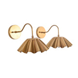 Angled perspective of two Cambria pleated brass wall sconces showcasing the sculptural scalloped shades and curved wall arms.