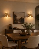 Pair of Cambria modern pleated brass wall sconces installed in a contemporary dining room, providing warm decorative ambient lighting.