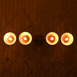 Capri Disc Linear Wall Light glowing warmly with four round disc shades on a patterned wall.
