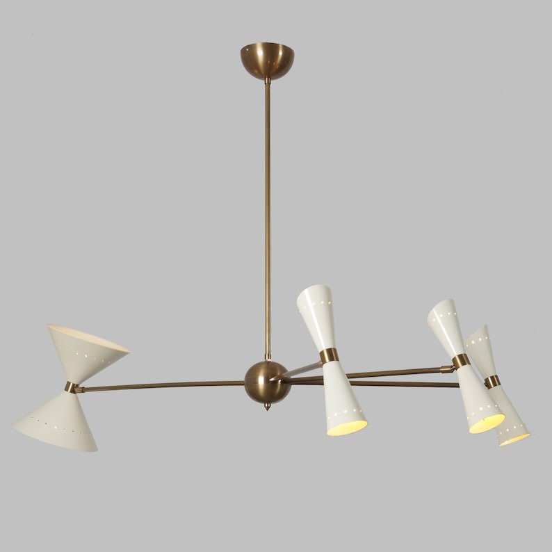 Angled view of the Catania 8-light Mid-Century Modern chandelier showcasing its tapered ivory cone shades, warm brass-tone frame, branching arms, and sculptural geometric design.