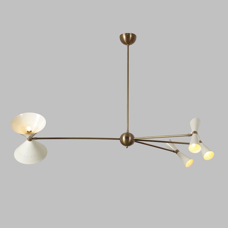 Catania 8-light asymmetric chandelier illuminated against a neutral background, highlighting its ivory cone shades, brass-tone metal arms, and warm multi-directional lighting.