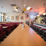 Catania 5 light brass-tone chandelier featuring black, red, yellow, mint green and cream cone shades shown from the front.