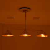 Charleston modern three-light chandelier displaying soft golden light from ivory cone shades in a moody evening setting.