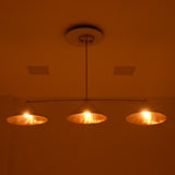 Front night view of Charleston 3-light linear chandelier with warm golden illumination beneath three conical metal shades.