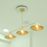 Charleston modern linear chandelier with three downward-facing ivory cone shades and brass-finish horizontal arms, illuminated from below.
