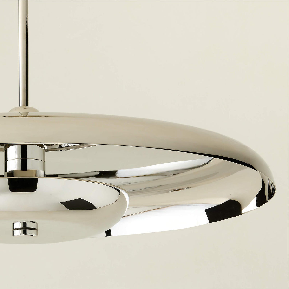 Close-up of chrome disc chandelier edge and underside showcasing smooth reflective finish and modern craftsmanship.