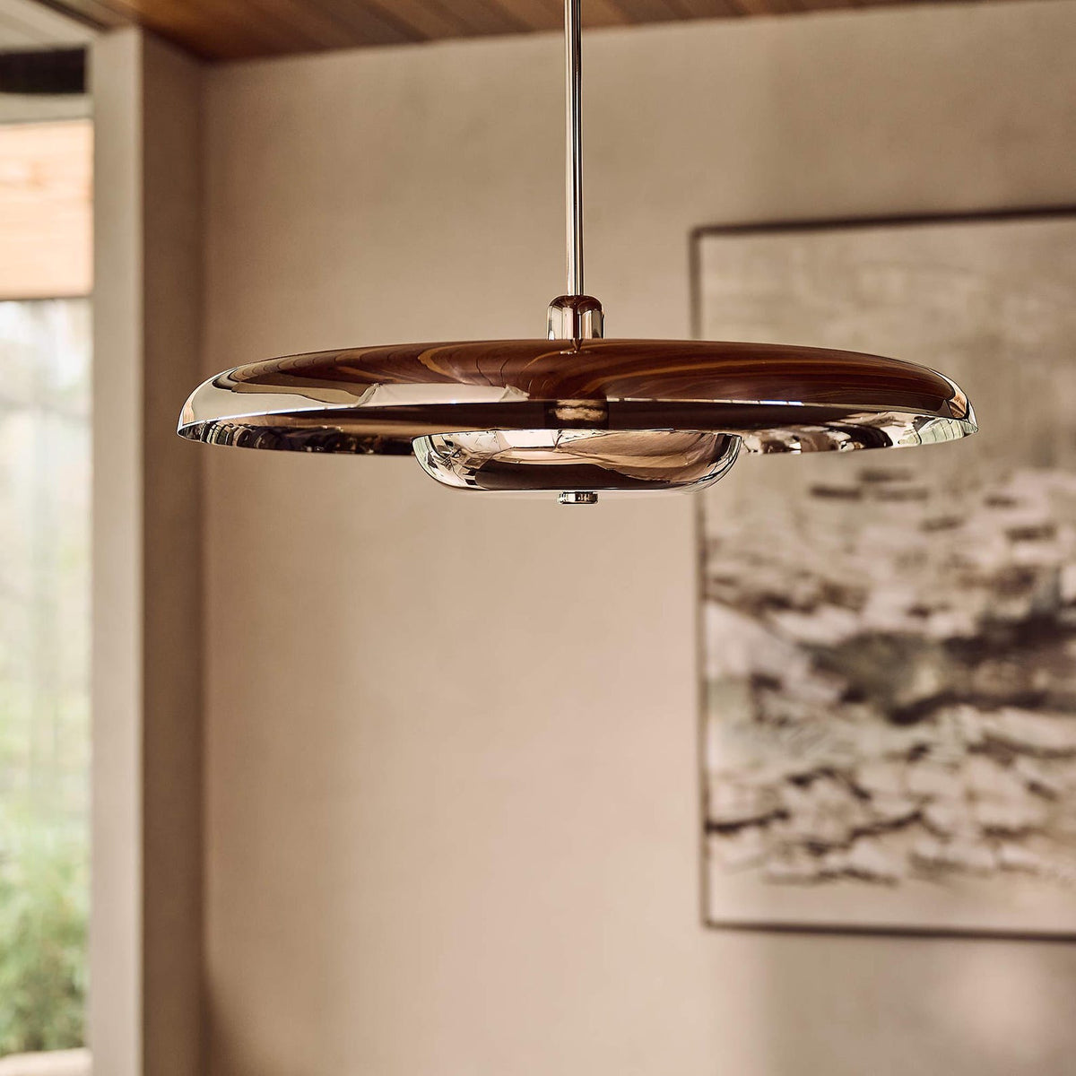 Polished chrome disc chandelier installed in modern interior, reflecting light with sleek sculptural elegance.