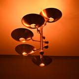 Low angle view of Como Orbital chandelier with glowing bowl shades and warm ceiling light effect.