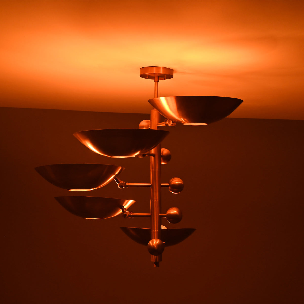 Como Orbital chandelier shown illuminated from the side, highlighting layered bowl shades and warm ambient glow.