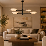 Straight front view of Como 4 light chandelier displaying four upward-facing white bowl shades arranged at different heights on a black metal frame.