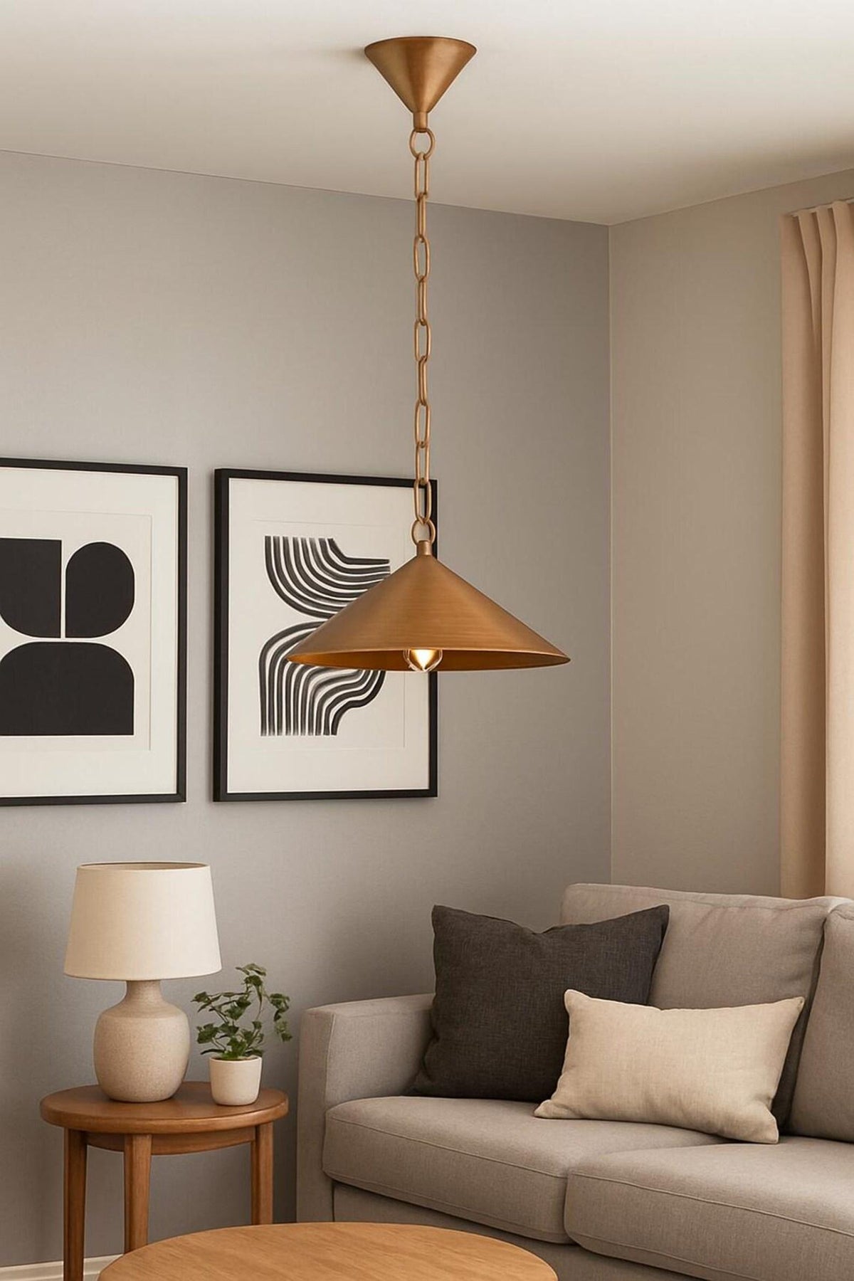 Brass cone pendant light with chain installed above a living room seating area with framed wall art.