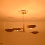 Dallas four-bowl sculptural ceiling chandelier shown at an angle with illuminated circular light openings and elegant brass construction.