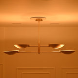Front view of Dallas four-light linear chandelier with a brass finish, two-tier bowl arrangement, and warm ambient evening illumination.