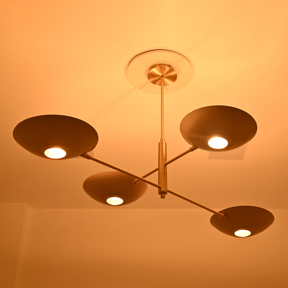 Close-up underside view of Dallas 4-light chandelier featuring shallow metal bowl shades, circular illuminated centers, and sleek brass arms.