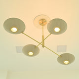 Dallas modern four-bowl chandelier viewed from below, featuring brass arms, circular light openings, and warm glowing illumination.