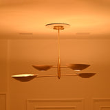 Side-angle view of Dallas 4-light brass chandelier highlighting its slim horizontal arms, staggered bowl shades, and warm decorative glow.