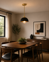 Delphi 1 light black and brass dome pendant displayed above a warm Mid-Century Modern dining table with dark wood furniture.