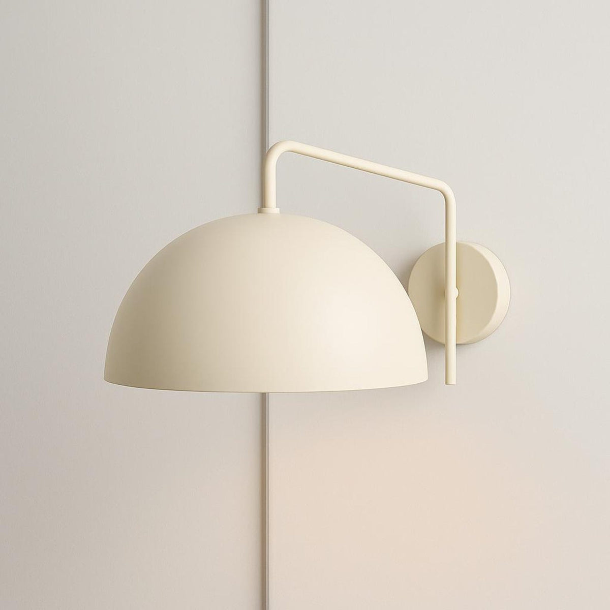 Monochrome cream dome wall sconce with matching arm and round backplate on a neutral wall.