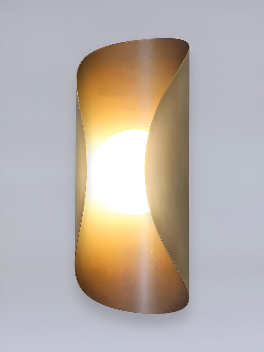Curved brass wall sconce with blackened exterior and brushed brass interior featuring a central frosted globe for soft ambient lighting