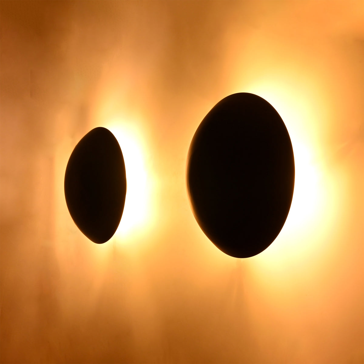 Angled view of the Eclipse modern black dome wall sconce highlighting its sculptural silhouette and warm halo illumination.