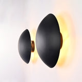 Side perspective of the Eclipse black dome wall sconce showcasing its curved dome shade, slim profile, and warm ambient backlighting.