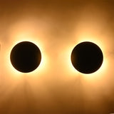 Eclipse black dome wall sconce creating a dramatic warm halo lighting effect with soft indirect illumination.
