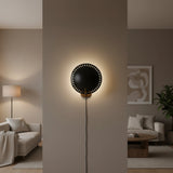 Front view of Eclipse 15 inch perforated disc wall sconce with dark circular shade and brass mounting details.