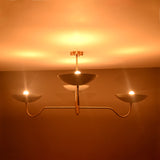 Florence Curved Arm chandelier with four glowing bowl shades and graceful arms creating warm ambient lighting.