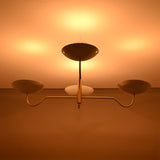 Florence Curved Arm chandelier shown illuminated, casting warm ceiling light from sculptural bowl shades.