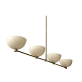Florence 4 light linear chandelier shown from an angled view highlighting its rounded cream bowl shades and slender brass-tone frame.