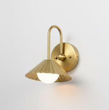 Side angle view of modern solid brass wall sconce with fluted shade and minimalist curved arm design