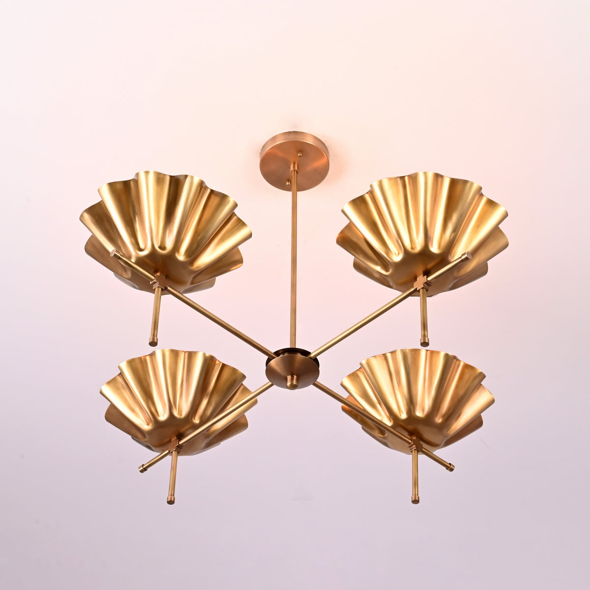 Overhead view of a four-arm brass bloom chandelier with sculpted shades, radiating elegance and symmetry.
