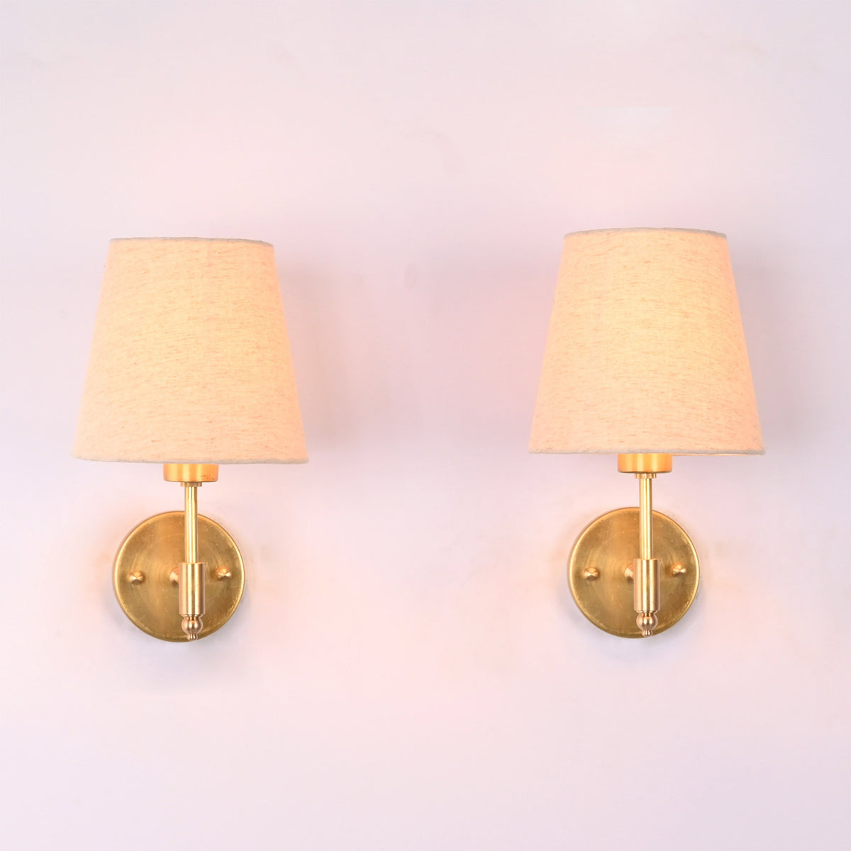 Milan natural linen shade brushed brass short wall sconce with handcrafted solid brass frame and tapered fabric shade, front view.