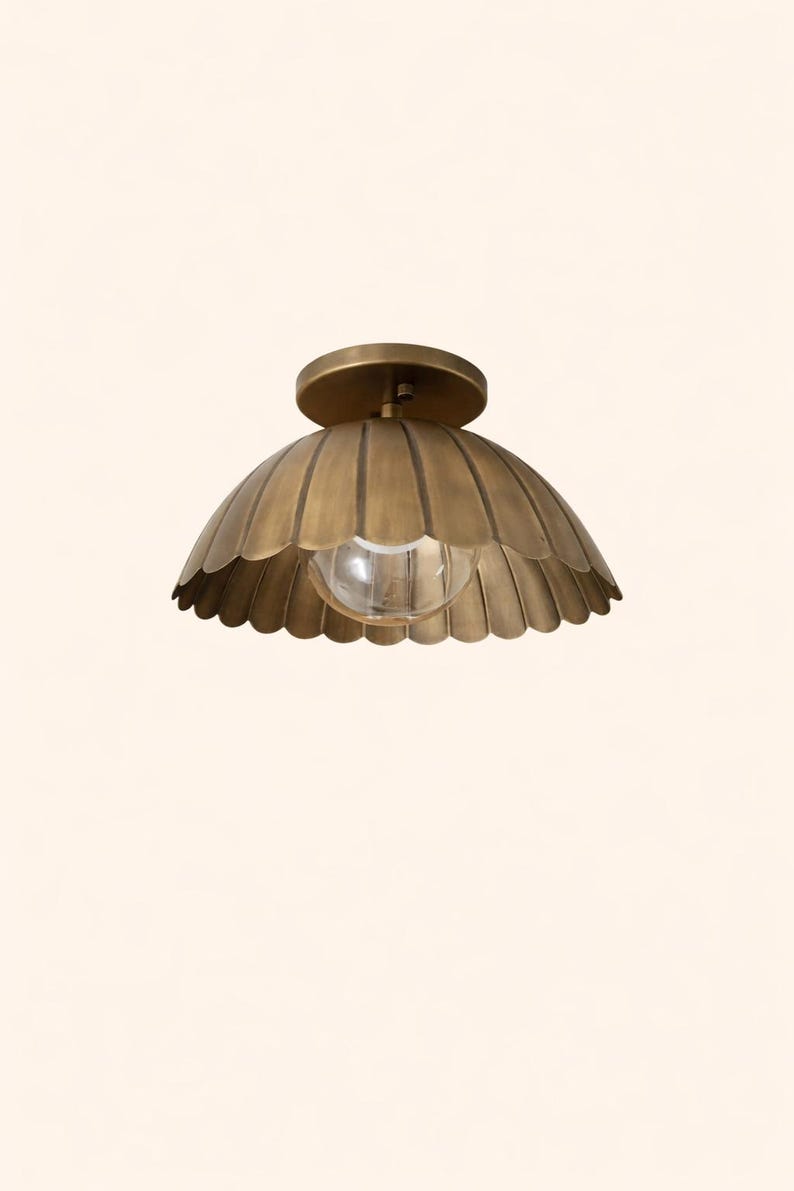 Brass scalloped dome flush mount ceiling light in brushed brass with warm glowing bulb, 12-inch flower bowl shade.