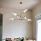 Frosted glass cone brass chandelier elegantly suspended above a dining table, casting soft ambient light in a modern home interior.