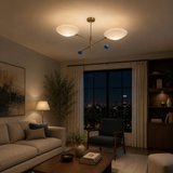 Geneva 2 light sculptural brass chandelier installed in a modern living room with illuminated white bowl shades and blue accents.
