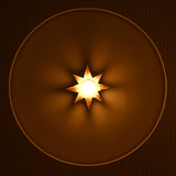 Front view of gold starburst wall sconce casting warm ambient light across a textured recessed wall.