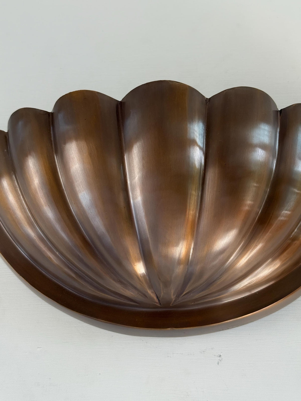 Close-up of half-flower brass wall sconce bowl shade highlighting fluted petal design and hand-finished bronze/aged brass patina.